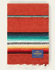 Red-orange sarape blanket with turquoise, black, white and yellow stripes