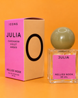 Pink and tan Icons Julia box beside a square glass perfume bottle with a pale green sphere cap, on an orange background