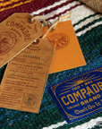 Compadre leather hang tags and woven brand label on a striped blanket