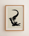 Framed artwork of a black silhouette of a woman and crocodile on a beige background