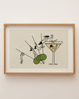 Framed artwork of a cocktail glass with a martini olive on a beige background