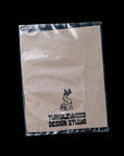Kraft paper bag with Tumbleweed Design Studio logo on a black background