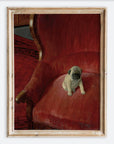 Framed artwork of a pug puppy on a red velvet chair