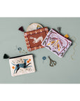 Three embroidered pouches with various designs on a light gray background