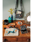 Collection of handcrafted bags and pouches on a wooden surface with decorative items.