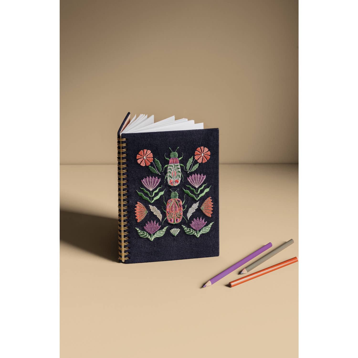 Empower your dreams with the Amulet Embroidered Notebook, featuring protective symbols and high-quality screen printing in a striking ring-bound design.
