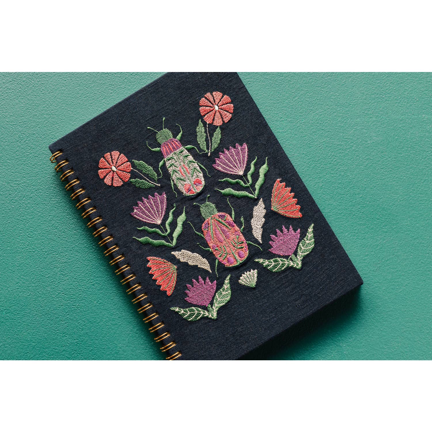 Empower your dreams with the Amulet Embroidered Notebook, featuring protective symbols and high-quality screen printing in a striking ring-bound design.
