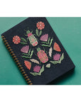 Empower your dreams with the Amulet Embroidered Notebook, featuring protective symbols and high-quality screen printing in a striking ring-bound design.