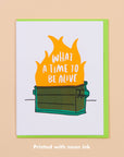 Card with flames and text 'What a time to be alive' on a beige background