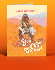 Birthday card with a person smoking in a desert scene, text 'Happy Birthday.