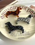 Show off your love for pups with this dachshund-shaped hair claw clip. Crafted from smooth brown acetate, it’s lightweight and easy to wear, keeping hair in place while adding a playful, whimsical touch to any look. Perfect for dog lovers or anyone who enjoys fun, animal-inspired accessories.