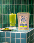 Haru Matcha Oat Milk Latte package on a tiled surface with a green drink.