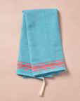 Brighten your kitchen with a pop of color and timeless charm. This striped woven tea towel blends function with simple elegance, featuring a refreshing aqua and white base accented by three bold red stripes at each end. Crafted from 100% cotton, it’s soft, absorbent and ready to tackle daily tasks - from drying dishes to lining a breadbasket. A convenient cotton loop in the corner makes it easy to hang and display. Whether you’re cooking up memories or cleaning up spills, this towel adds a cheerful, artisan