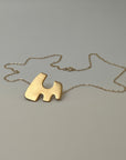 A silver, copper, and brass pendant necklace with a geometric cut-out design, displayed against a plain background.