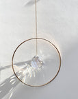 Bring a little sparkle and magic into your home with Prism Ring Suncatchers. Each piece features a golden ring with a prism suspended at its center, designed to catch sunlight and scatter tiny rainbows across your walls and floors. Hang it in a bright window or on a wall to add a touch of light-filled beauty to your space.