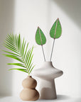 Bring a pop of color and artistry to your home with this handcrafted stained glass mulberry leaf stem by Samara Designs Studio. This stem is made from transparent earthy green stained glass with copper accents, evoking the solid, grounding tones of nature. Each piece is carefully handmade to create a lasting botanical accent that will never wilt or fade.