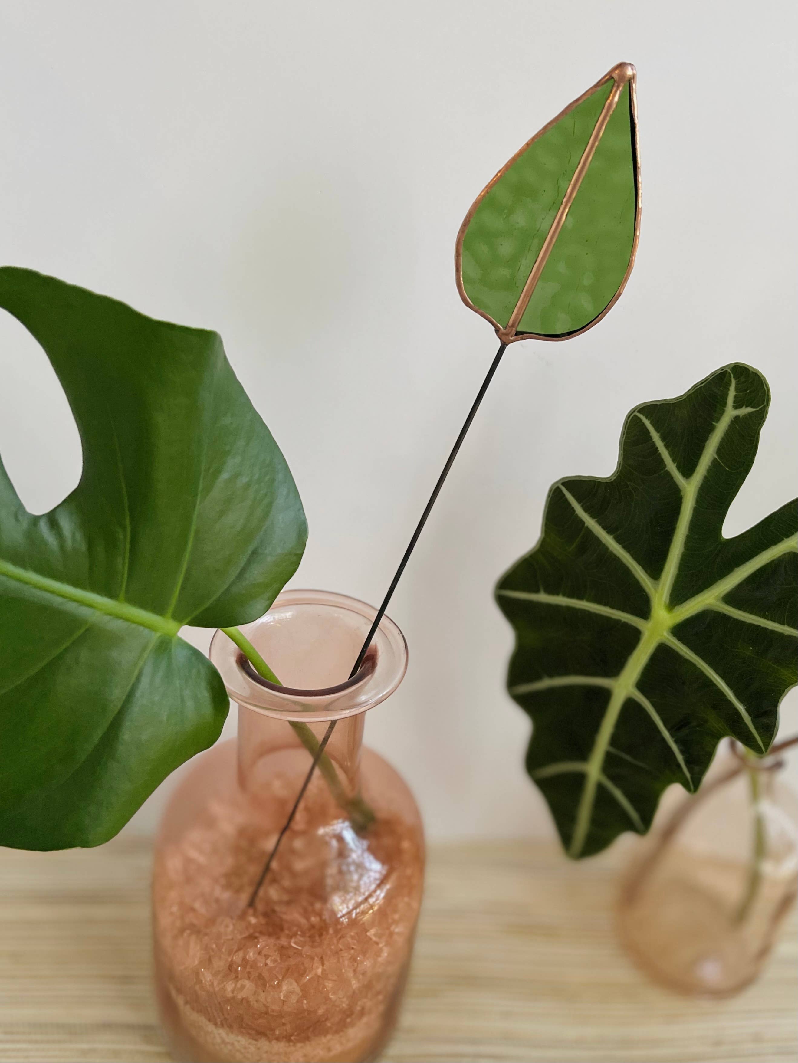 Bring a pop of color and artistry to your home with this handcrafted stained glass mulberry leaf stem by Samara Designs Studio. This stem is made from transparent earthy green stained glass with copper accents, evoking the solid, grounding tones of nature. Each piece is carefully handmade to create a lasting botanical accent that will never wilt or fade.