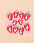 Sticker with strawberry design and 'Cute as a Button' text on a beige background