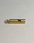 Brass whistle keychain lying on its side on a light gray background