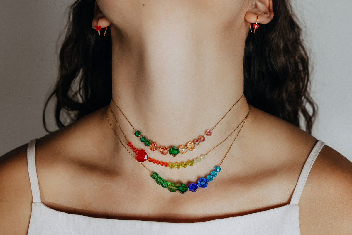 Woman in a white camisole wearing three layered crystal bead necklaces