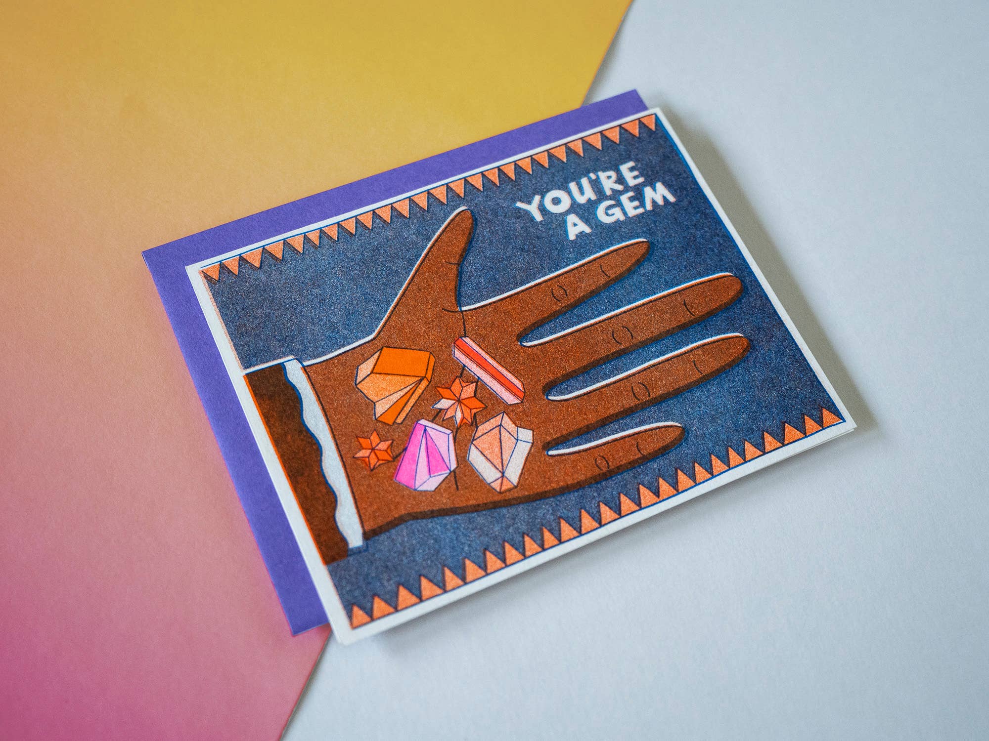 Greeting card with a hand holding gemstones and 'You're a Gem' text on a gradient background