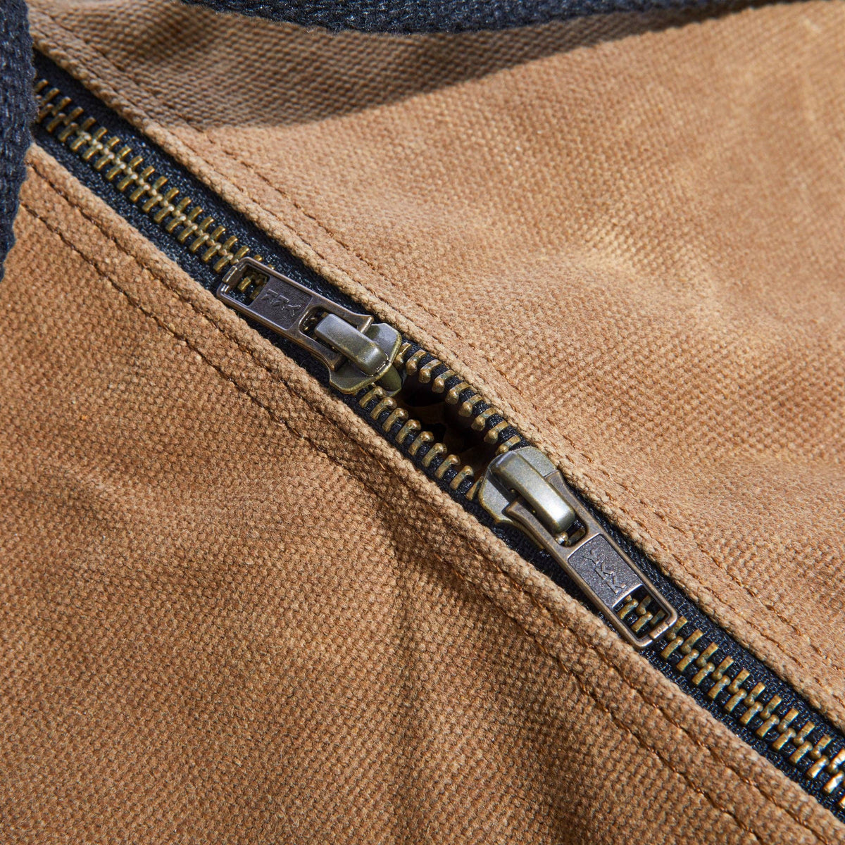 Waxed canvas duffel bag with webbing straps, padded handle and brass zipper