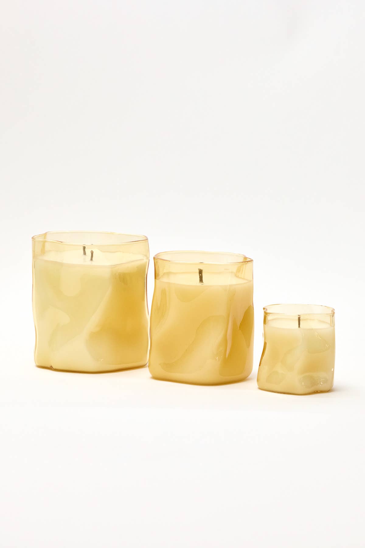 Three Choice Blooms candles in crinkled amber glass in large, medium and small sizes on a white background