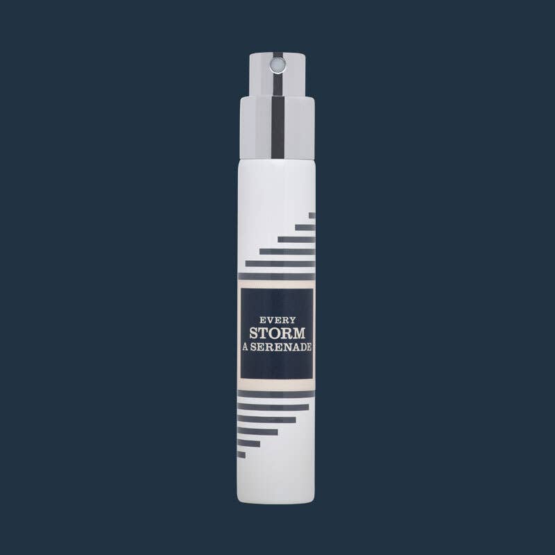 White Imaginary Authors travel spray with a navy Every Storm a Serenade label on a dark navy background