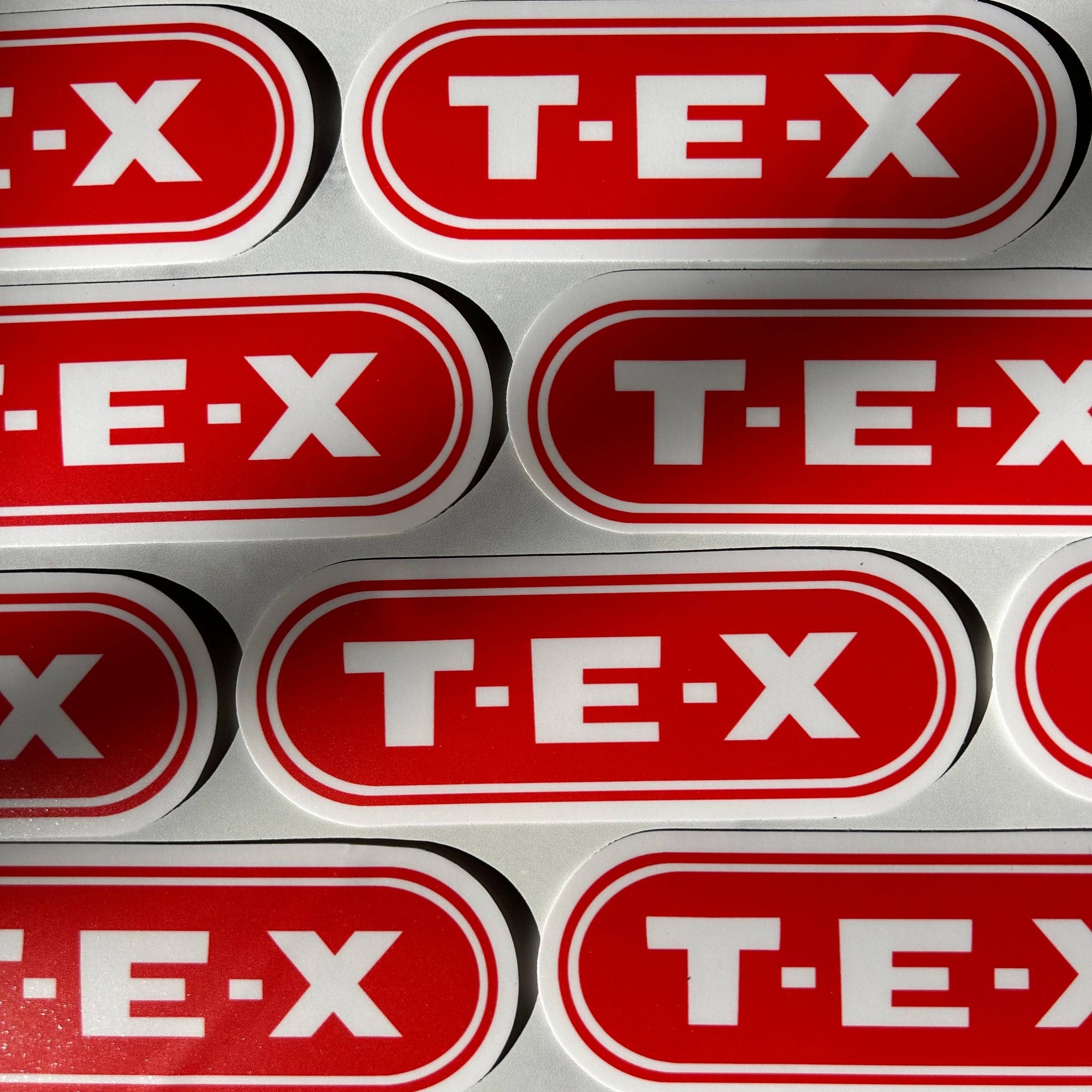 Multiple T-E-X logos arranged in a grid on a red background