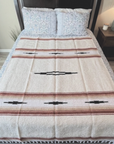 Cream Desert Mesa blanket with red stripes and black diamonds spread across a bed