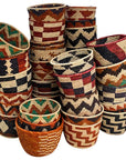 Stack of handwoven baskets in assorted rust, black, cream and green zigzag and checkered patterns