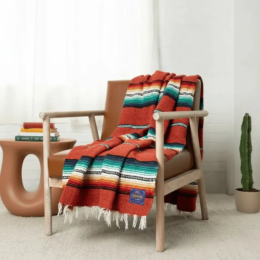Red-orange sarape with turquoise, black and white stripes draped over a wooden armchair