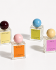 Whitney, Dolly, Betsey and Julia perfume bottles with colored sphere caps on a white background