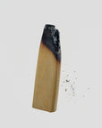 Burnt stick of palo santo wood with a little ash on a pale gray background
