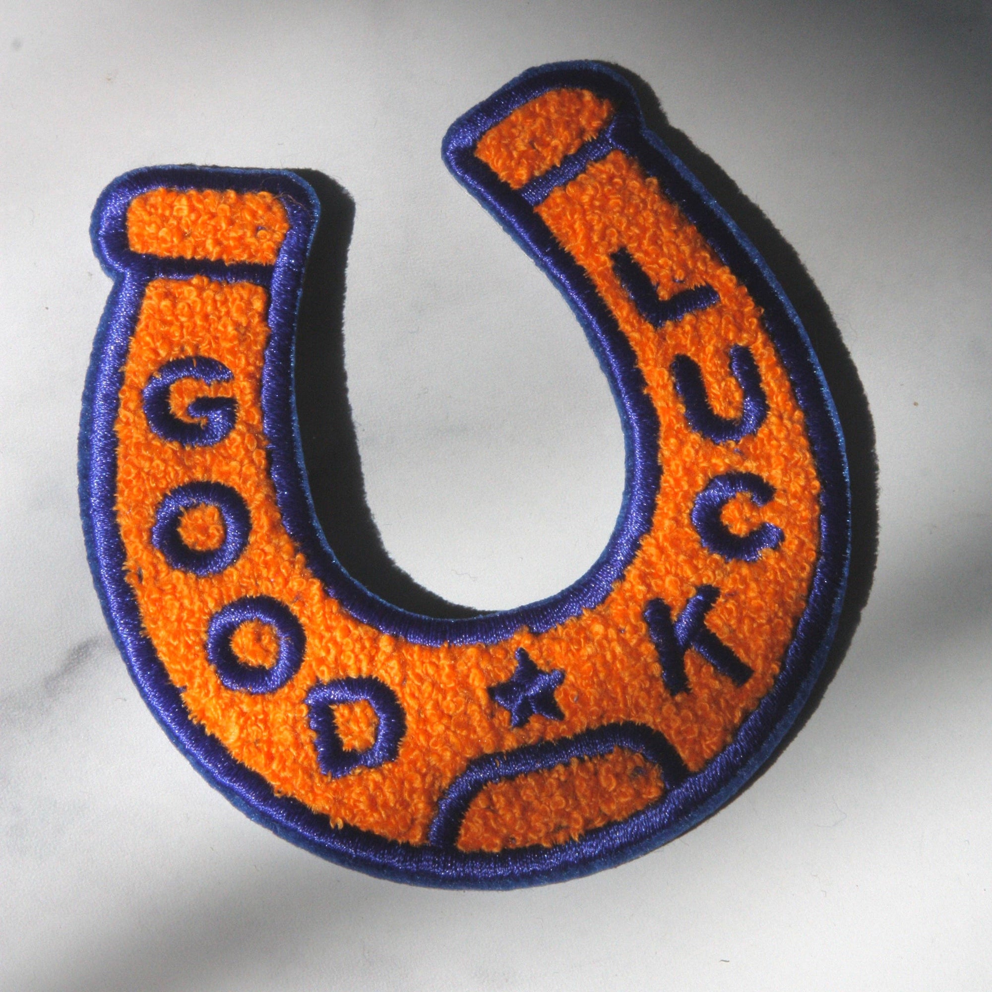 Orange and purple horseshoe-shaped patch with text on a white background
