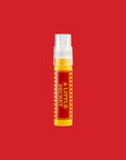 Yellow A Little Secret travel spray with a red label, on a red background