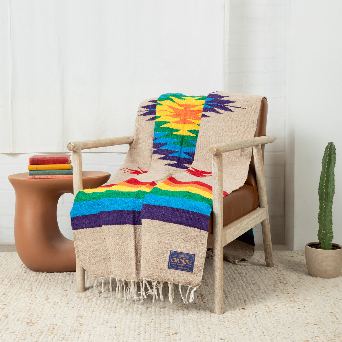 Cream blanket with a colorful Southwest star and rainbow stripes draped over a wooden armchair