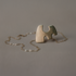 Sculptural pendant necklaces on chains with a white stone on a gray background