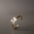 Año sculptural cuff bracelet with a cut-out edge on a dark gray background