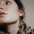 Close-up of a woman in a leopard coat wearing a clear blown glass sphere earring