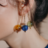 Close-up of an ear wearing amber, cobalt and green blown glass drop earrings