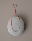 Round stone with red string and turquoise bead on a beige background