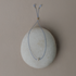 Gray silk cord bracelet with a tiny gemstone bead draped on a round stone