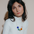 Woman in a white turtleneck wearing the Jūra necklace of colored blown glass spheres