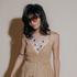 Model in sunglasses and a tan dress wearing a cobalt blue glass sphere necklace