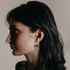 Woman with long dark hair in profile wearing a green blown glass hoop earring