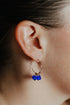 Close-up of an ear wearing a gold hoop with three cobalt blue crystal cubes
