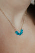 Close-up of a model wearing a blue crystal arc necklace on a fine gold chain