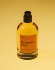 A 50ml bottle of 'dilo' Satsuma Oud Eau de Parfum with amber-colored liquid, a black spray nozzle, and an orange label, set against a warm yellow gradient background.