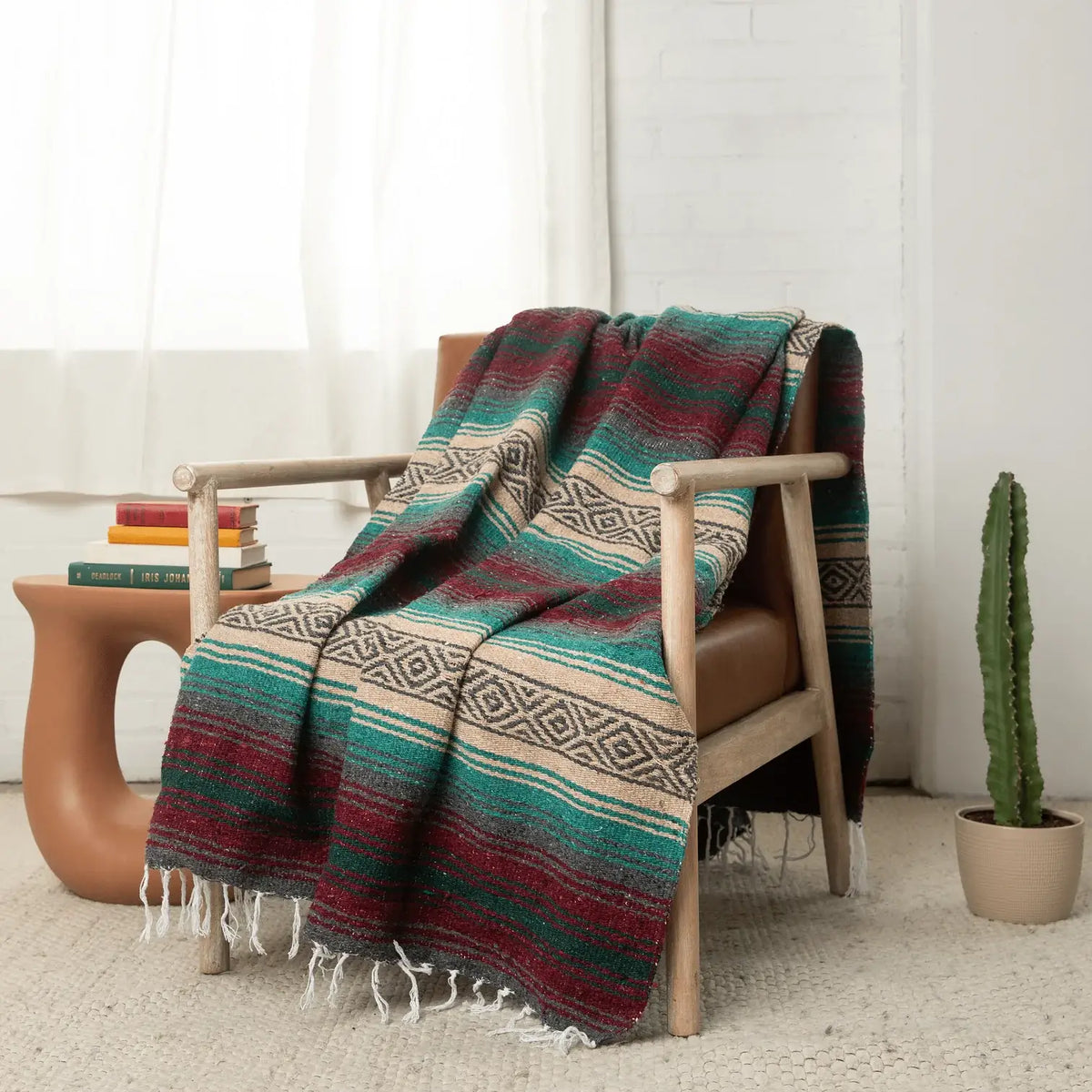 Maroon, teal and tan striped falsa blanket draped over a wooden armchair